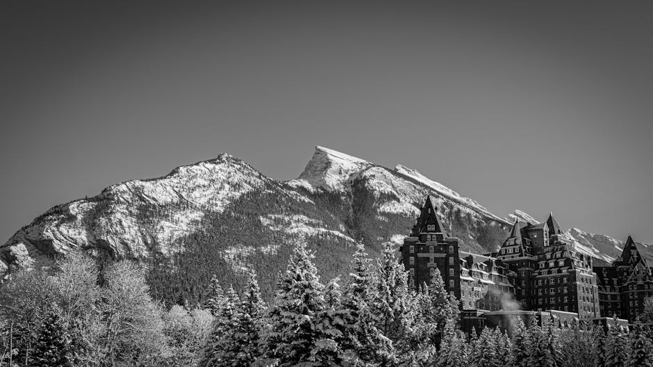 Dramatic black and white photo of a mountain scene with a historic hotel.